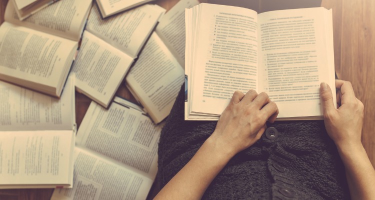 Woman reading a few books on the floor