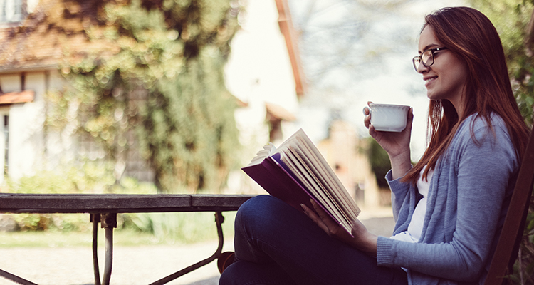 Woman drinking tea and reading a book