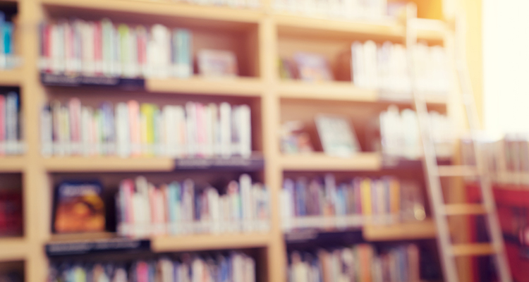 blurred bookshelf in library room for your background design - vintage color styles.
