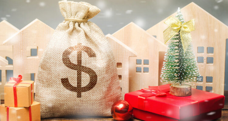 Money bag, wooden houses, Christmas tree and gifts. Holiday discounts. Christmas sale of real estate. New Year discounts for buying housing. Purchase apartments at a low price. Favorable prices